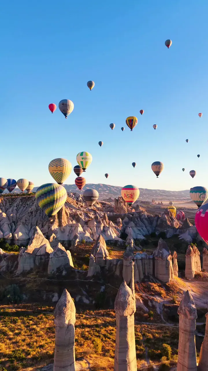 Dozens of hot-air balloons rising above Cappadocia's valleys at sunrise