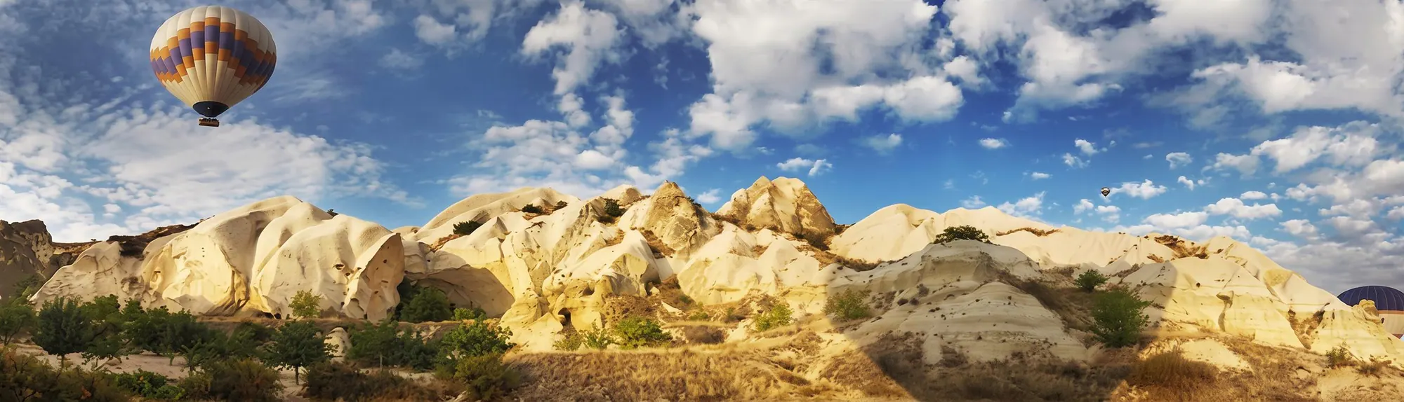 A hot-air balloon floating over Cappadocia’s pale rock landscape
